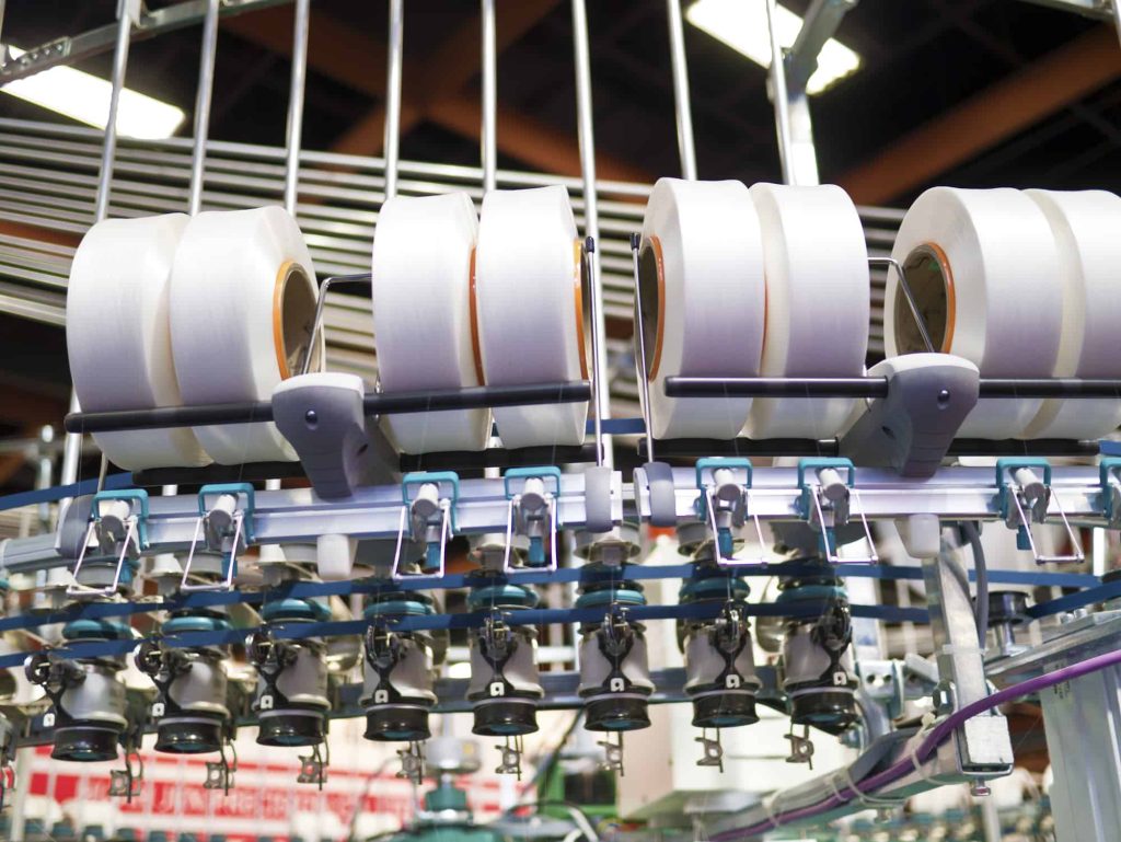 Textile industry - yarn spools on spinning machine in a textile factory