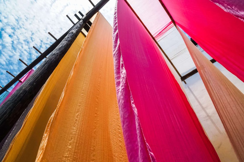 colourful fabric hanging to dry after traditional dye process