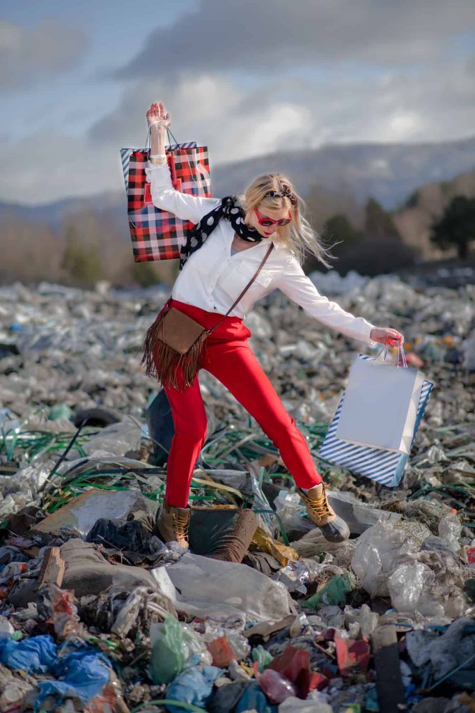 Fashionable woman on landfill, consumerism versus pollution concept.