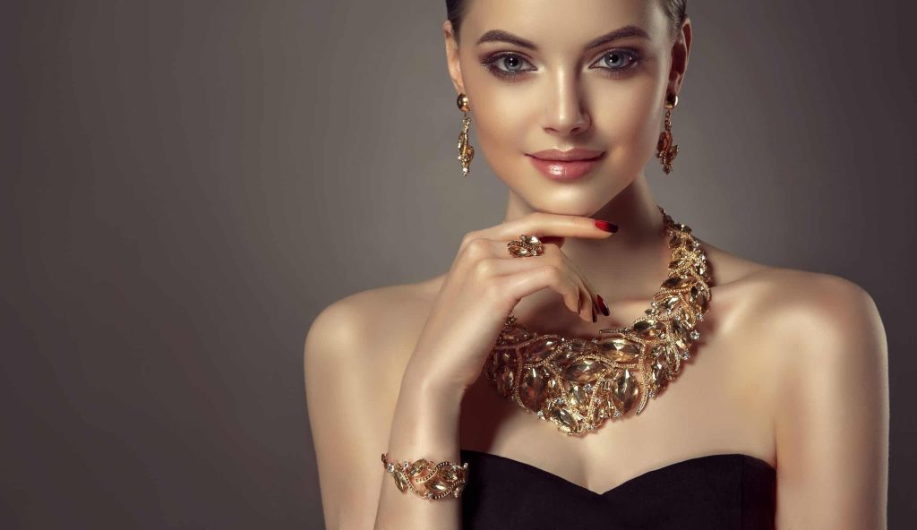 Woman wearing a gold necklace and earrings.
